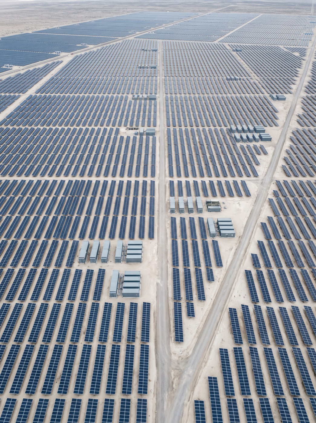 A utility-scale solar array with storage enclosures stretching to the horizon